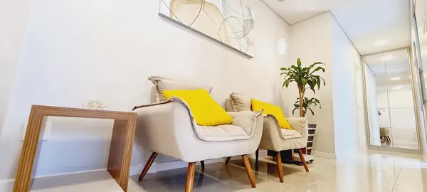 Sala de espera Dra. Jociene com poltronas ergonômicas e almofadas amarelas para conforto durante espera por tratamentos avancados